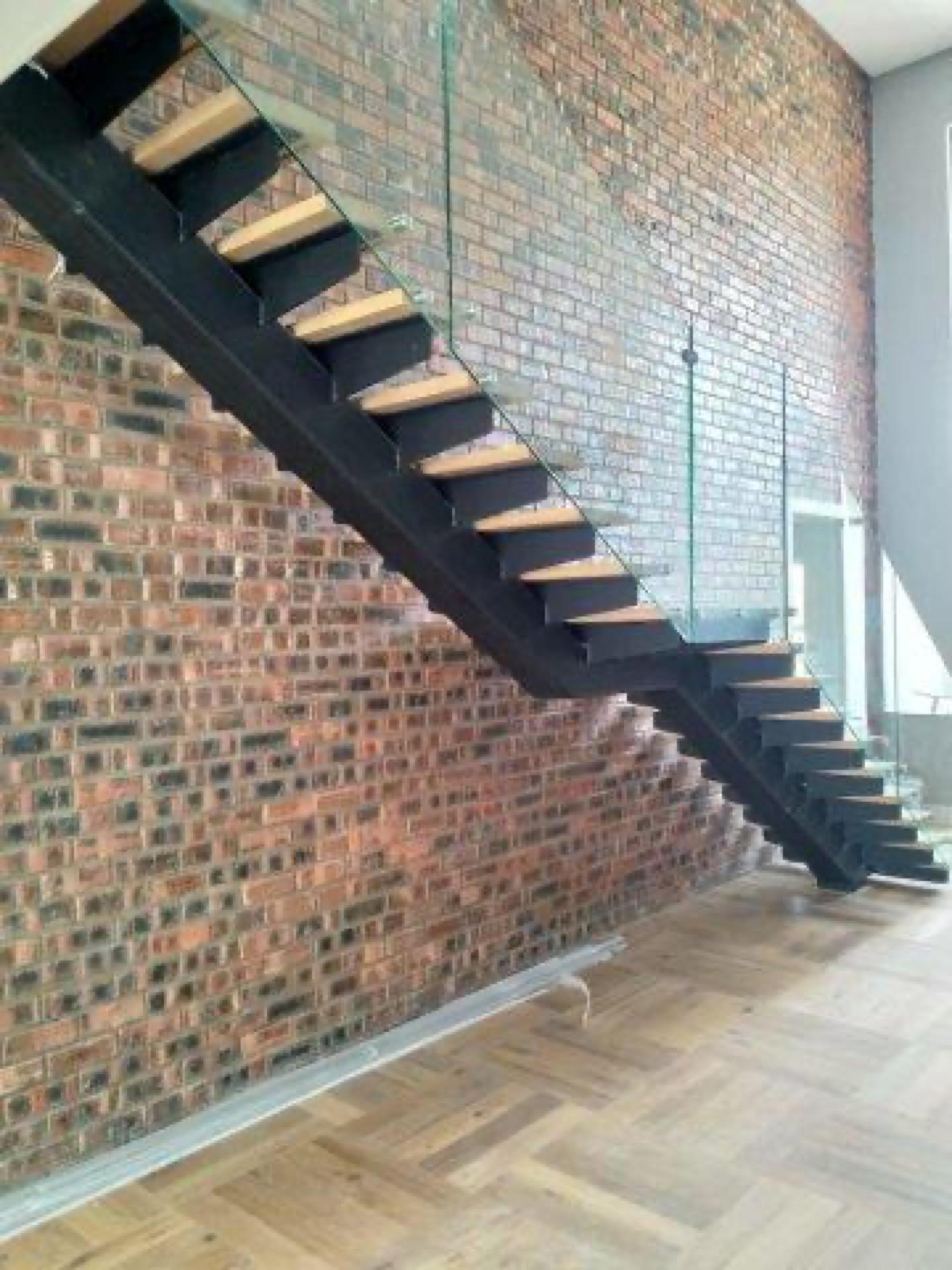 Architectural steel staircase with exposed brick by Sterianos